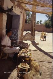 Image du Maroc Professionnelle de  Un artisan marocain fabrique des chaussures, de chapeaux de paille, et de vannerie en raphia, une fabrication artisanale faite main dont la production est très prisée par la population. Son Atelier se situe dans une rue à l'ancienne Kasbah de  Ouarzazate où résident les berbères du sud du Maroc, le Vendredi 22 Août 1997. (Photo / Abdeljalil Bounhar)

